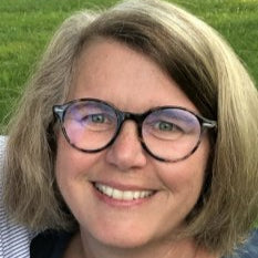Person with glasses smiling outdoors