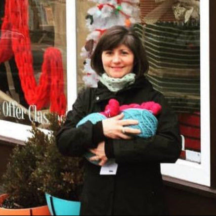 Woman holding a knitted item in front of a store window display